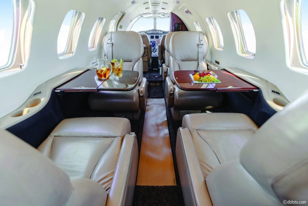 Cessna Citation Bravo cabin looking forward to the cockpit, with drinks and fruit on the club-seat worktables