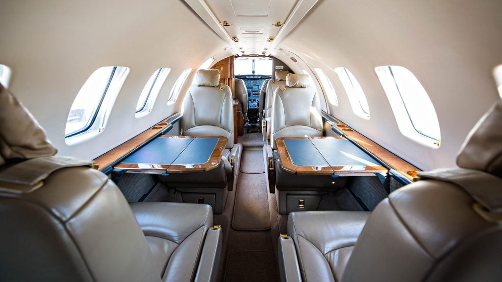 Cessna Citation V cabin with cream leather club seats and wood-trim worktables, looking forward to the cockpit